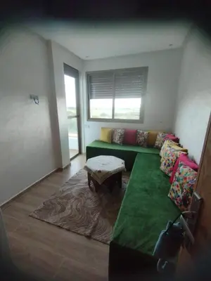 a living room with a green couch and a table at appartement jinane in Bouznika