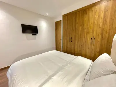 a bedroom with a white bed and a wooden cabinet at E19 Appt Moderne & Calme à Maarif ,Casablanca in Maarif