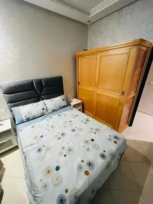 a bedroom with a bed and a wooden cabinet at appartement sublime in Oulad Hamida