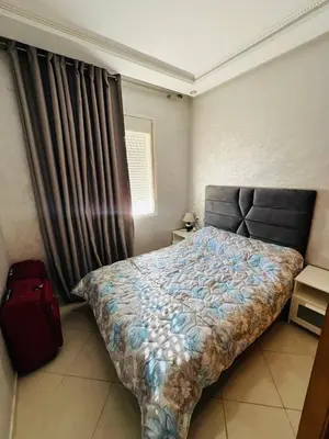 a bedroom with a bed and a red suitcase at appartement sublime in Oulad Hamida