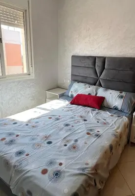 a bed with a red pillow on it in a bedroom at appartement sublime in Oulad Hamida