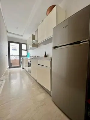 a kitchen with a stainless steel refrigerator and white cabinets at Appartement centre casablanca in Maarif