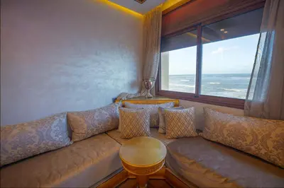 a living room with a couch and a large window at Spacious Beachfront apartment in Casablanca