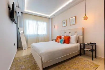 a bedroom with a large white bed with orange pillows at Appartement Moderne au Cœur de Rabat by MERAT HOME in Océan