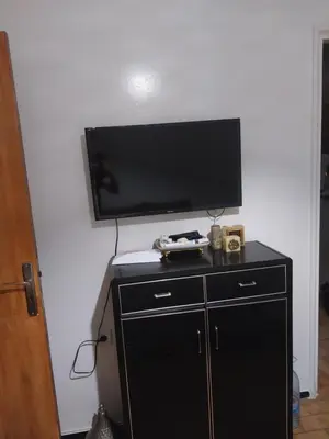 a flat screen tv on a wall with a black cabinet at Assabah apartement in Kouas