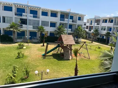 a playground in front of a large building at Très bel Appartement avec Piscine et Jardin in Mansouria