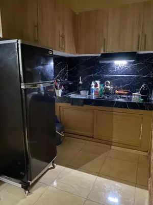 a kitchen with a black refrigerator and wooden cabinets at Magnifique Studio Gare - Tram in Les Camps