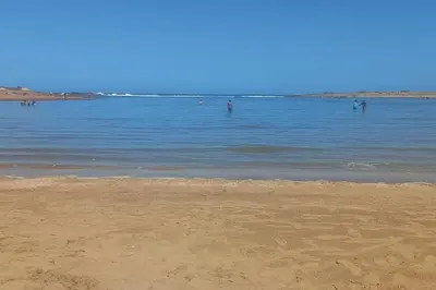 a beach with people swimming in the water at Appart familial près de la plage Val d'or in El Harhoura