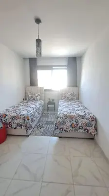 a bedroom with two beds in a white room at Appart familial près de la plage Val d'or in El Harhoura