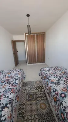 a room with two beds and a rug at Appart familial près de la plage Val d'or in El Harhoura