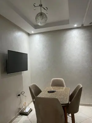 a dining room with a table and chairs and a flat screen tv at Appartement Oasis beach in Pont Blondin