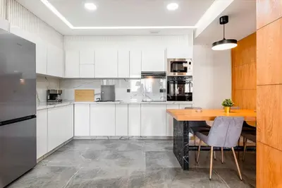 a kitchen with white cabinets and a wooden table at Modern and Luxurious apartment in Rabat