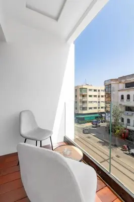 a white chair sitting in a room with a large window at Modern Elegance in City Core in Gare de Rabat-Aguedal