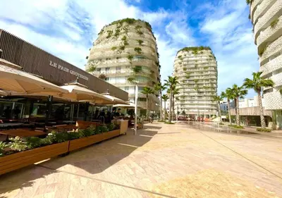 a street with two tall buildings and buildings with trees at Les Tours Végétales, Casablanca Finance City in Casablanca