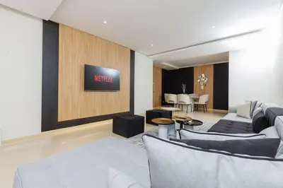 a living room with a couch and a tv on a wall at Elegant 2BR in Hay Riad - New Furnishings & Design in Beni Brour