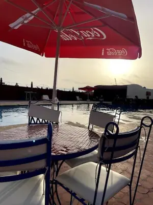 a table and chairs with an umbrella on a beach at Casa Jnane Jawhara Skhirat in Rabat