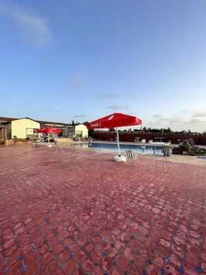 a patio with an umbrella and a table and chairs at Jnane Jawhara Skhirat house in Skhirat