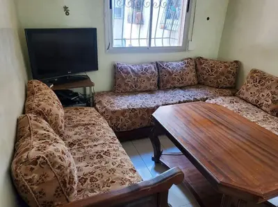 a living room with a couch and a table at à 10 minutes du grand mall d'Afrique, WiFi Netflix 1ère étage in Oulad Hamida