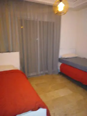 a bedroom with two beds and a window with curtains at Appartement in Casablanca