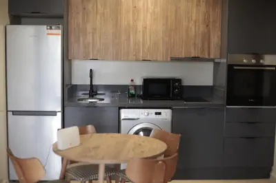 a kitchen with a table and a small kitchen with a stove and refrigerator at Studio cosy à Maârif, Palmiers in Maarif
