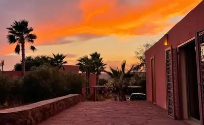 a painting of a sunset behind a red building at Kasbah Oum Rabia in Boulaouane