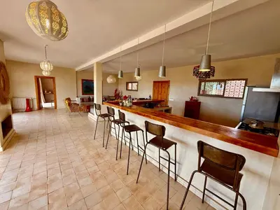 a room with a bar with chairs and a kitchen at Kasbah Oum Rabia in Boulaouane