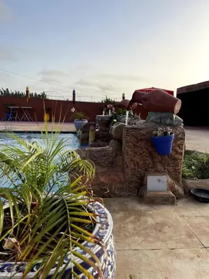 a swimming pool with a fountain in a yard at Jnane Jawhara Skhirat studio in Skhirat