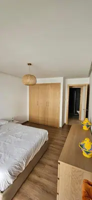 a bedroom with a large white bed and wooden floors at le carrousel Rabat Océan in Kouas