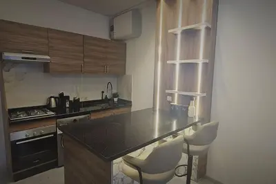 a kitchen with a black counter top and white chairs at Chic & Charme Studio Près de l'aéroport in Nouaceur