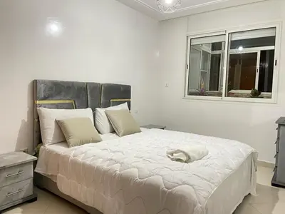 a bedroom with a large white bed with a window at Charmant appt 2 ch terrasse in Rabat