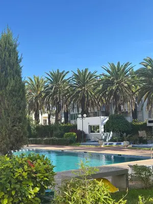 a swimming pool with palm trees in the background at Duplex Chic & Design Unique au bord de la mer ! in Mohammedia