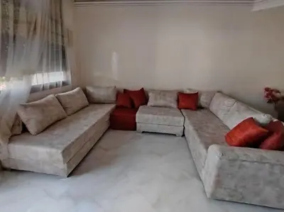 a living room with a large couch and red pillows at Joli Apparemment et calme in Casablanca