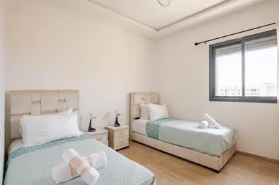 a bedroom with two beds and a window at Residence GYA Beach - Luxe Moderne et Confort à Harhoura accès plage in Temara