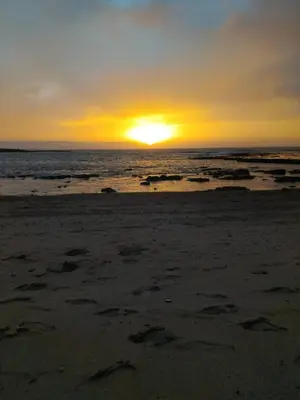 a sunset on the beach with footprints in the sand at Appartement Confortable en Résidence Privée avec Piscine in Pont Blondin
