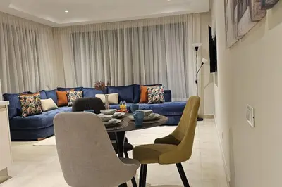 a living room with a blue couch and a table and chairs at Emplacement Central & So Stylish Près du Consulat Américain 2 minutes de Twin Center Gauthier Casablanca in Casablanca