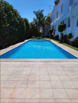 a large blue swimming pool next to a house at Lovely 2 bedroom flat in Ain Diab in Casablanca