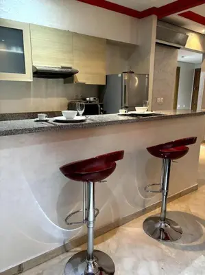 a kitchen with two bar stools at a counter at Votre chez-vous à Casa, une ambiance cosy garantie in Casablanca