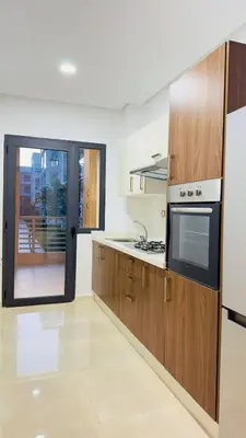 a kitchen with wooden cabinets and a microwave at Cosy Suite Appart in Bouznika
