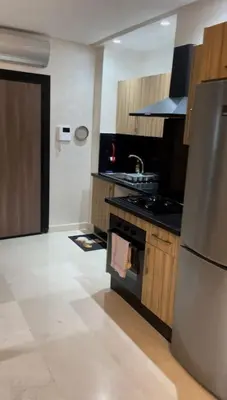 a kitchen with a refrigerator and a stove top oven at Apparemment 300 m de la plage, Parc Mohammedia in Mohammedia