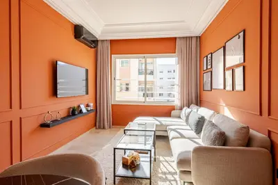 a living room with orange walls and a couch at The 23 Princesses by IB Signature - Stylish 2 Bedroom Apt with Wifi, Self check-in - 24 x7 Security - City View - Walk to Cafes! City Centre in Casablanca