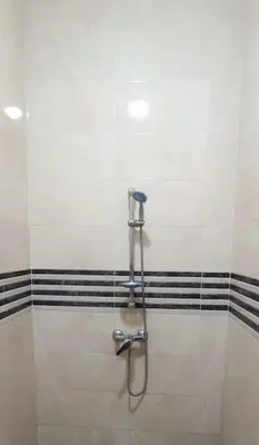a shower in a bathroom with black and white tiles at appartement calme in Casablanca