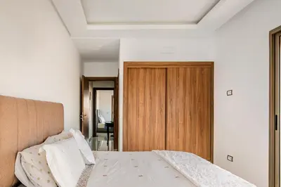 a bedroom with a bed and a wooden door at Appartement luxueux avec piscine dans une résidence calme in Bouznika