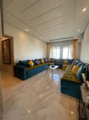 a living room with a couch and a table at Appart avec Piscine Proche de la Mer in Bouznika