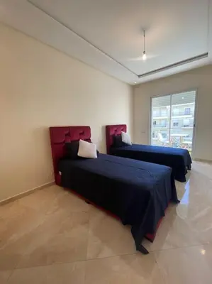 a bedroom with two beds and a window at Appart avec Piscine Proche de la Mer in Bouznika