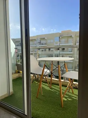 a table and chairs on the balcony of a building at Appart avec Piscine Proche de la Mer in Bouznika
