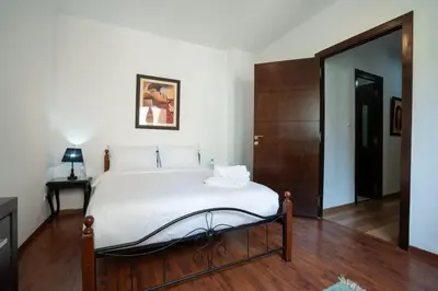 a bedroom with a large white bed and a wooden floor at Appartement Cosy Proche du Stade in Rabat