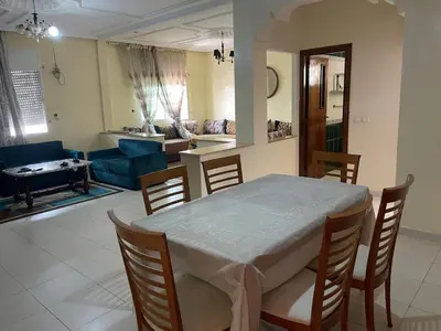 a dining room and living room with a table and chairs at Appt à Harhoura in El Harhoura