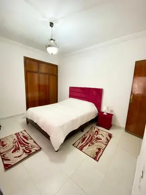 a bedroom with a large bed and two rugs at Appt à Harhoura in El Harhoura