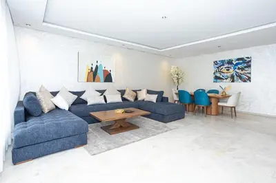 a living room with a blue couch and a table at Appartement géant in Rabat