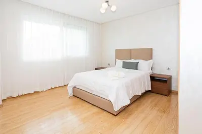 a white bedroom with a large bed and a window at Appartement géant in Rabat
